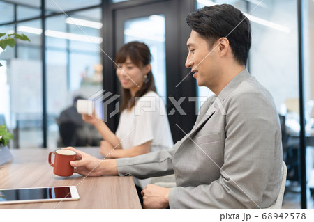 オフィスの共有スペース(コワーキングスペース)で会話をする上司と女性部下 68942578