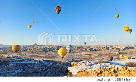 Colorful hot air balloons flying over the valley with fairy chimneys in winter season. Lots of Hot air balloons at the sunrise sky landscape in Cappadocia, Turkey 68943684