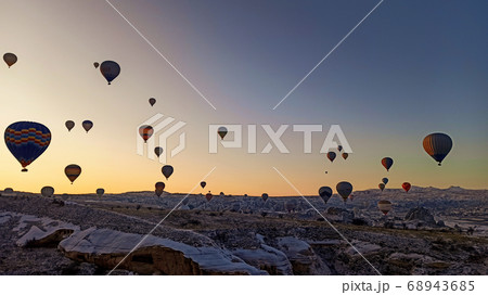 Colorful hot air balloons flying over the valley with fairy chimneys in winter season. Lots of Hot air balloons at the sunrise sky landscape in Cappadocia, Turkey 68943685