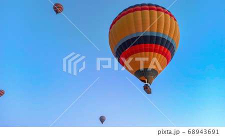 Colorful hot air balloons flying over the valley with fairy chimneys in winter season. Lots of Hot air balloons at the sunrise sky landscape in Cappadocia, Turkey 68943691