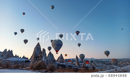 Colorful hot air balloons flying over the valley with fairy chimneys in winter season. Lots of Hot air balloons at the sunrise sky landscape in Cappadocia, Turkey 68943698