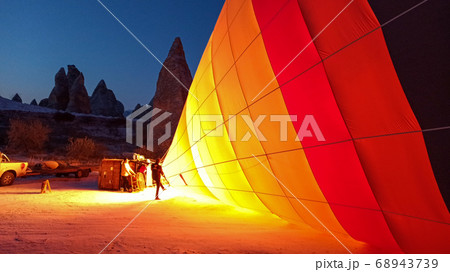 Colorful hot air balloons flying over the valley with fairy chimneys in winter season. Lots of Hot air balloons at the sunrise sky landscape in Cappadocia, Turkey 68943739