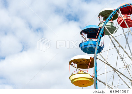 Colorful cabs of ferris wheels on the cloudy sky 68944597