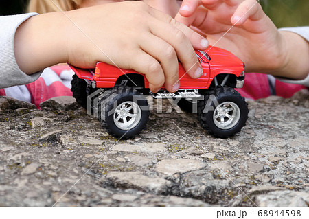 Children's hands hold a toy red car 68944598