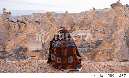 Woman alone with the volcanic landscape at Devrent Valley in Cappadocia. Girl walking around Fairy chimneys surronded by tufa formations at Imaginary Valley in winter season in Cappadocia, Turkey. 68944827