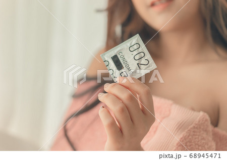 Happy girlfriend is holding a thing size condom 68945471