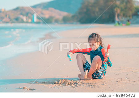 Little girl is playing with wave and sand on the 68945472