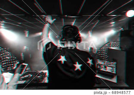 back of a male DJ with a raised hand in headphones back of a male DJ with a raised hand in headphones 68948577