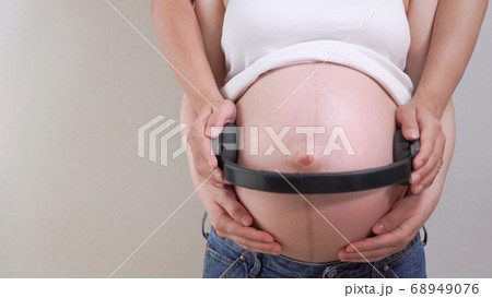 臨月の妊婦さんのお腹にヘッドホンを当てて胎教しているシーンの写真素材