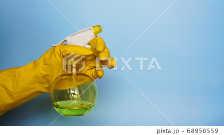 Hand in yellow rubber glove holding plastic spray bottle with cleaning detergent Hand in yellow rubber glove holding plastic spray bottle with cleaning detergent 68950559