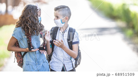 Two young friends classmates with face masks talk Two young friends classmates with face masks talk 68951509