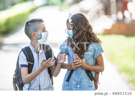Two young friends classmates with face masks talk Two young friends classmates with face masks talk 68951510