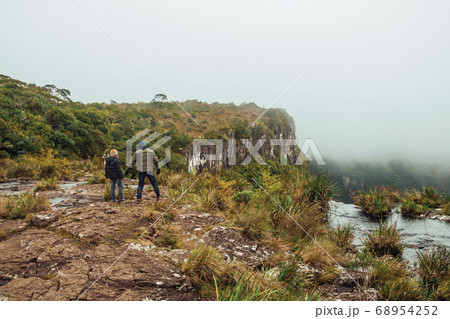 People on the edge of rocky cliff and mist 68954252