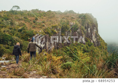 People on the edge of rocky cliff and mist 68954253