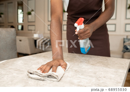 Hands of young waiter with detergent and duster cleaning table after clients 68955030