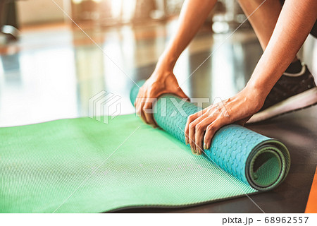 Close up of sporty woman folding yoga mattress in 68962557