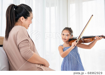 Girl playing violin with her pregnant mother for 68962929