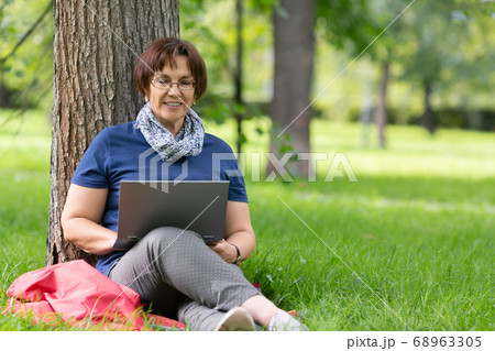 Smiling senior woman working remotely on a laptop in the city Park. Distant work concept 68963305
