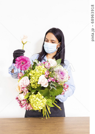 Cute woman florist is making a bouquet of roses, 68963918