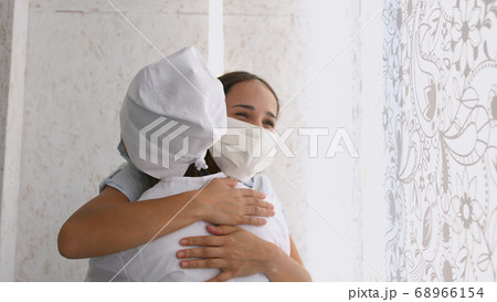 Smiling young female patient in mask with female doctor in white uniform thanking for help or feeling excited about healthcare treatment results at meeting. Smiling young female patient in mask with female doctor in white uniform thanking for help or feeling excited about healthcare treatment results at meeting. 68966154