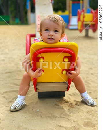 Cute little baby girl sits on a swing at the Cute little baby girl sits on a swing at the 68966225