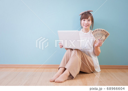 パソコンとお金を持った笑顔の女性 パソコンとお金を持った笑顔の女性 68966604