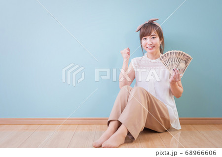 お金を持ってガッツポーズをする笑顔の女性 お金を持ってガッツポーズをする笑顔の女性 68966606