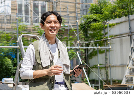 工事現場でスマホを使う作業員の若い男性 工事現場でスマホを使う作業員の若い男性 68966683