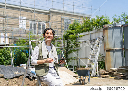 工事現場でスマホを使う作業員の若い男性 68966700