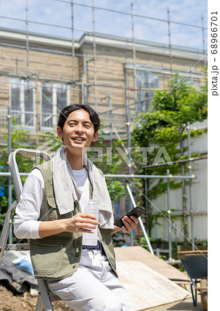 工事現場でスマホを使う作業員の若い男性 工事現場でスマホを使う作業員の若い男性 68966701