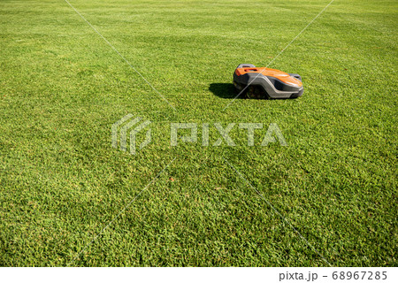 Automatic lawn mower robot moves on the green grass 68967285