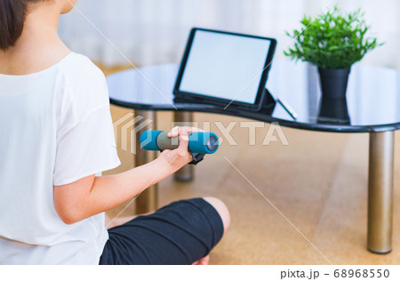 リビングで配信動画を見つつダンベル運動をする若い女性【ニューノーマルのライフスタイル】 68968550