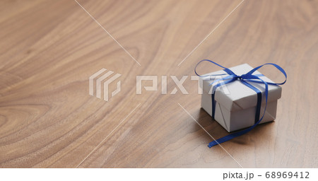 white paper gift box with blue ribbon on walnut table with copy space 68969412