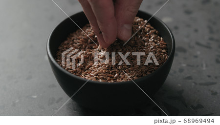 closeup of man hand takes flaxseed from black bowl closeup of man hand takes flaxseed from black bowl 68969494