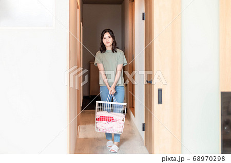 自宅で洗濯物を運ぶ若い主婦 自宅で洗濯物を運ぶ若い主婦 68970298