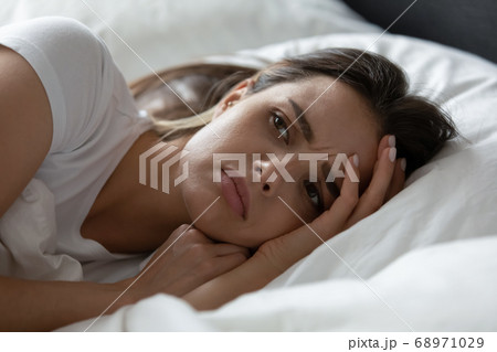 Close up stressed young woman lying in bed alone Close up stressed young woman lying in bed alone 68971029