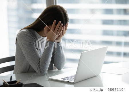 Frustrated overworked businesswoman covering face with hands, sitting at desk Frustrated overworked businesswoman covering face with hands, sitting at desk 68971194