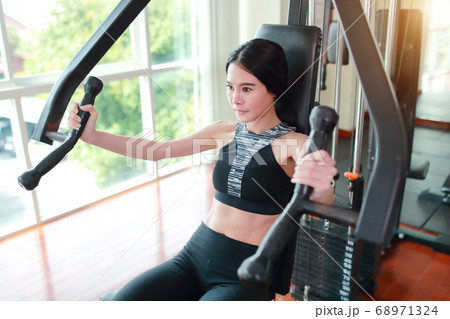 portrait of young healthy and sporty woman using exercise machine in gym portrait of young healthy and sporty woman using exercise machine in gym 68971324