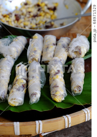 doing Vietnamese vegetarian dish, make deep fried corn spring roll, vegan food in leaf background doing Vietnamese vegetarian dish, make deep fried corn spring roll, vegan food in leaf background 68971529