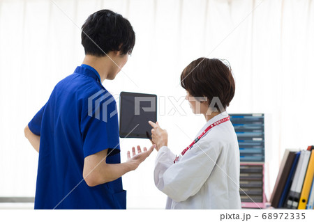 タブレットを見て相談する医療従事者 68972335