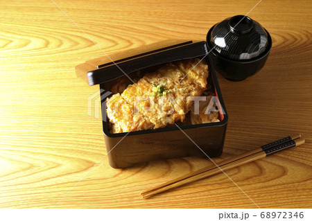 玉ねぎが入っていたり万能ねぎが乗っていたりするかつ重とお椀とお箸 68972346