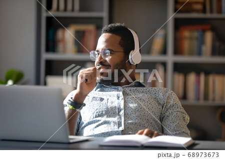 Dreamy smiling African American man wearing headphones looking to aside 68973673