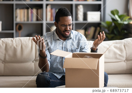 Angry irritated African American man dissatisfied by received parcel 68973717