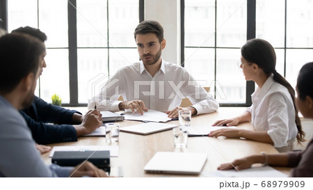 Millennial male mentor instructing mixed race teammates at workplace. 68979909