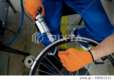 Worker with machine tool installs new bicycle rim Worker with machine tool installs new bicycle rim 68981512