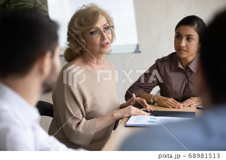 Confident middle aged senior businesswoman talking to employees. 68981513