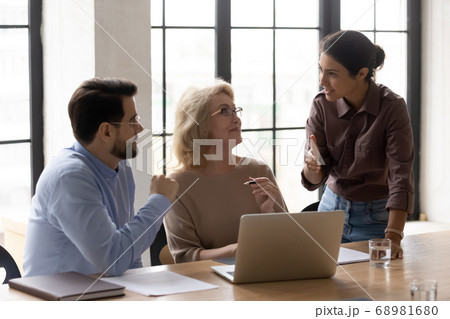 Diverse business people discussing online project in office. Diverse business people discussing online project in office. 68981680