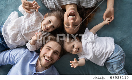Happy young parents relaxing on bed with joyful little daughters. Happy young parents relaxing on bed with joyful little daughters. 68983119