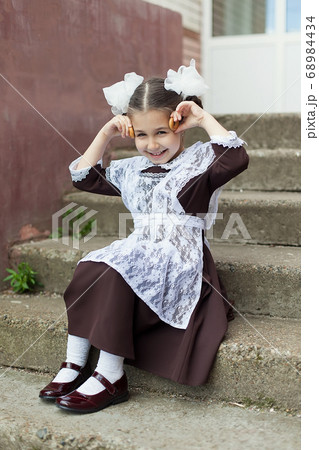 a little girl in a school uniform plays with the steering wheel. Retro photo. School. 68984434