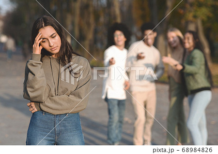 Sad muslim girl staying aside from group of teenagers Sad muslim girl staying aside from group of teenagers 68984826